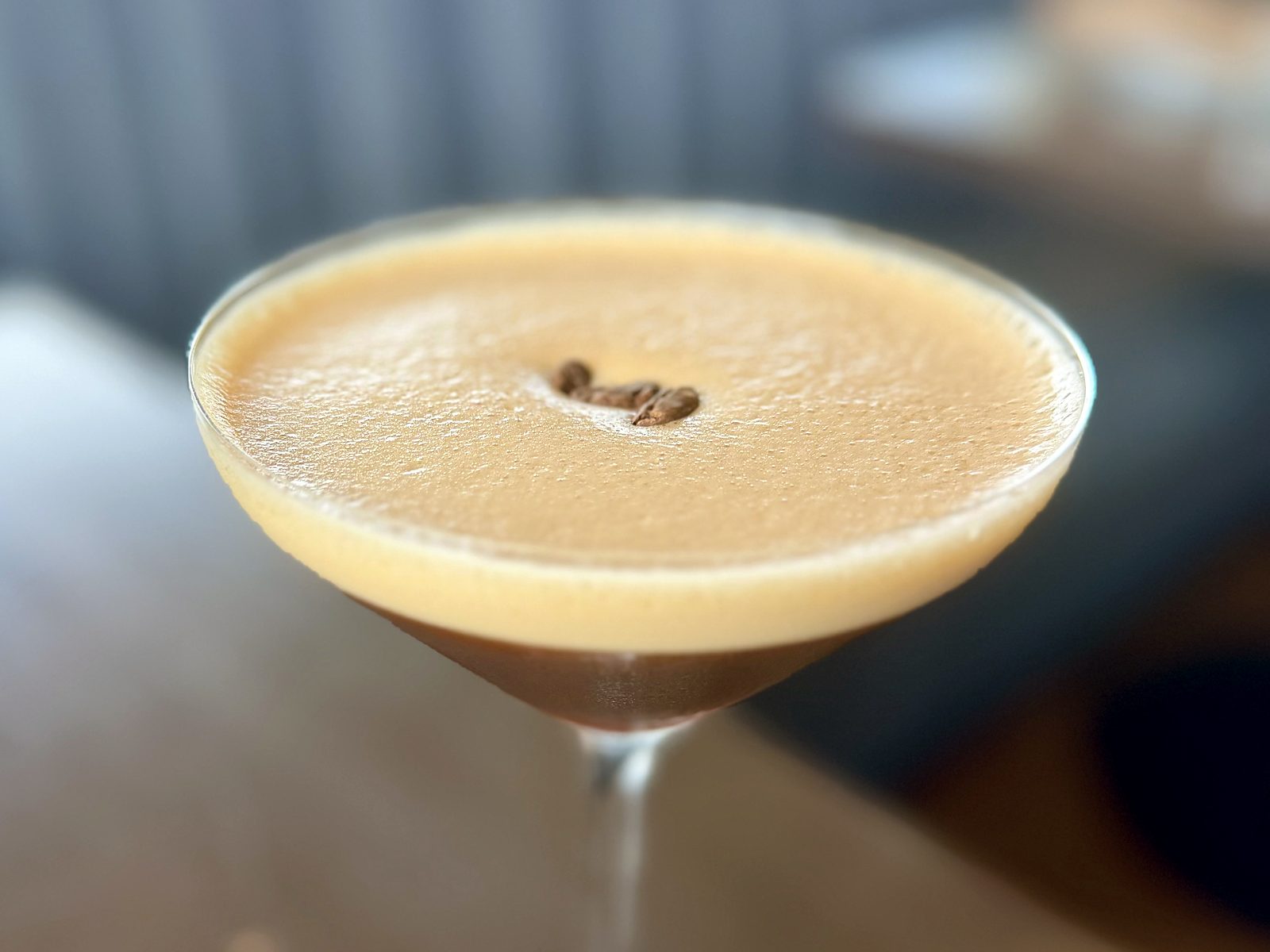 The Night Shift at Acre — a cold brew martini capped with a dense foam crown and three coffee beans.