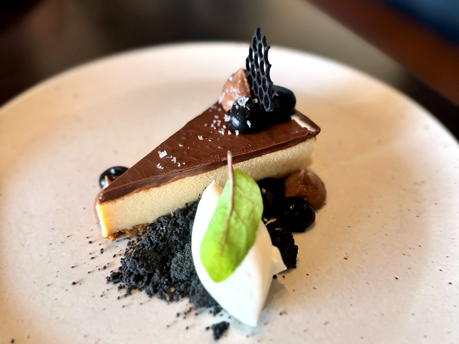 A slice of peanut butter pie at Acre — dark chocolate ganache top with flaky salt, chocolate crumble, whipped cream, and a honeycomb tuile.