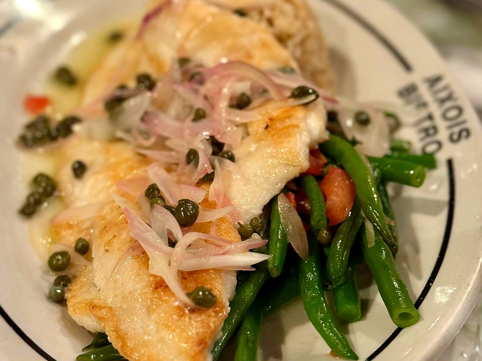 Halibut at Aixois — a pan-seared fillet over haricots verts, dressed with capers, shaved shallots, and beurre blanc.