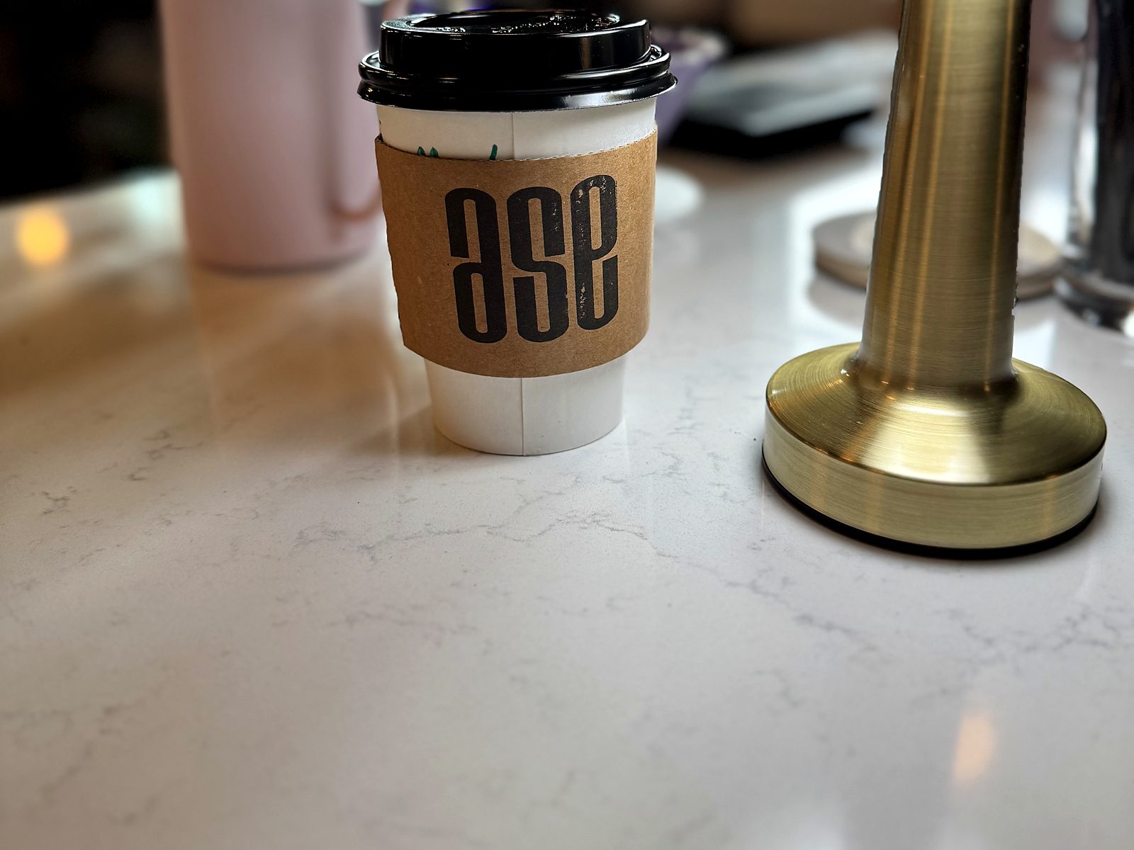 Coffee to go at Ase Coffee, in a sleeve stamped with the shop's lowercase logo.
