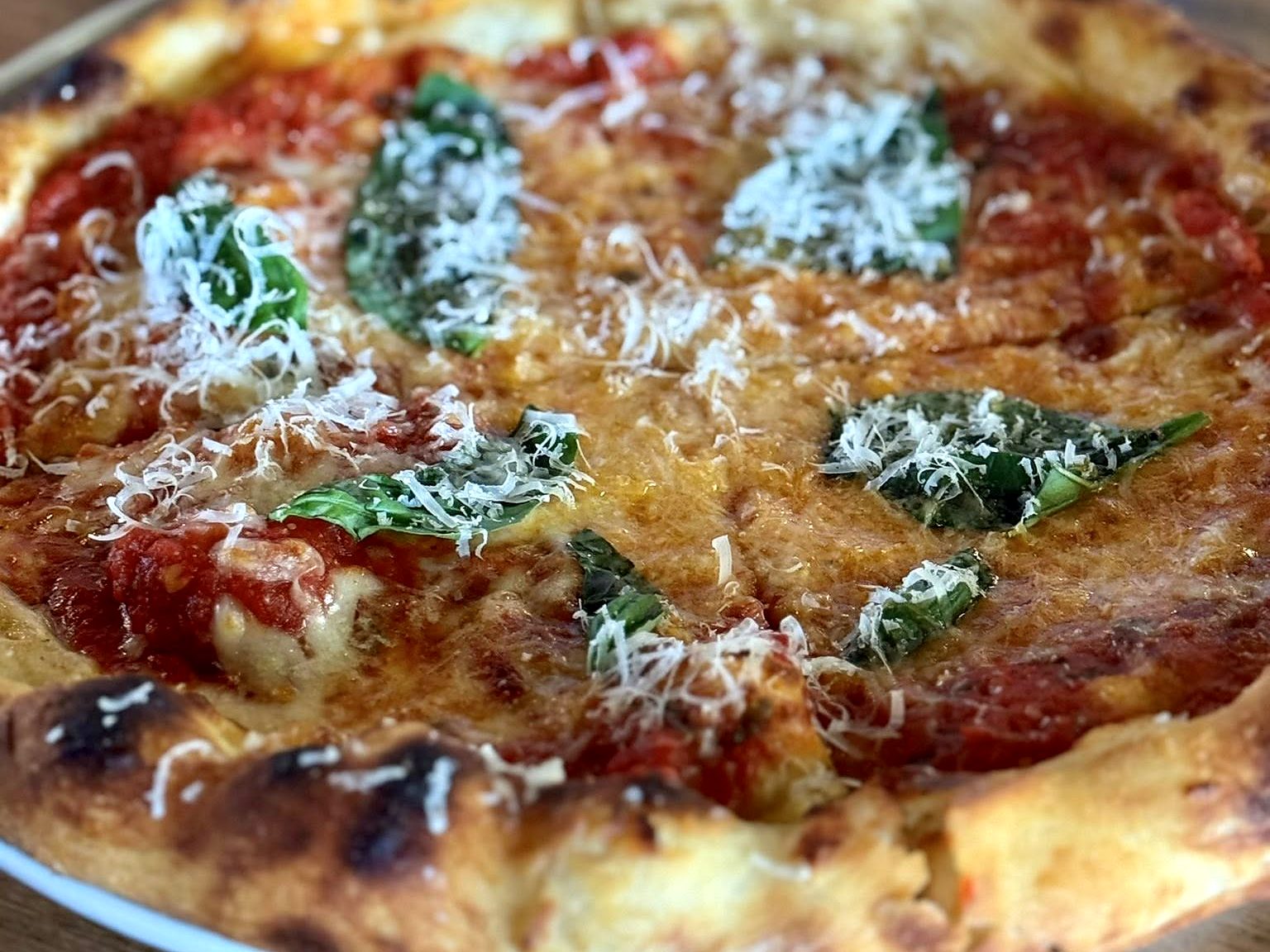 The margherita at Osteria Bianchi — blistered crust, tomato, basil, and mozzarella under a snowfall of grated cheese.