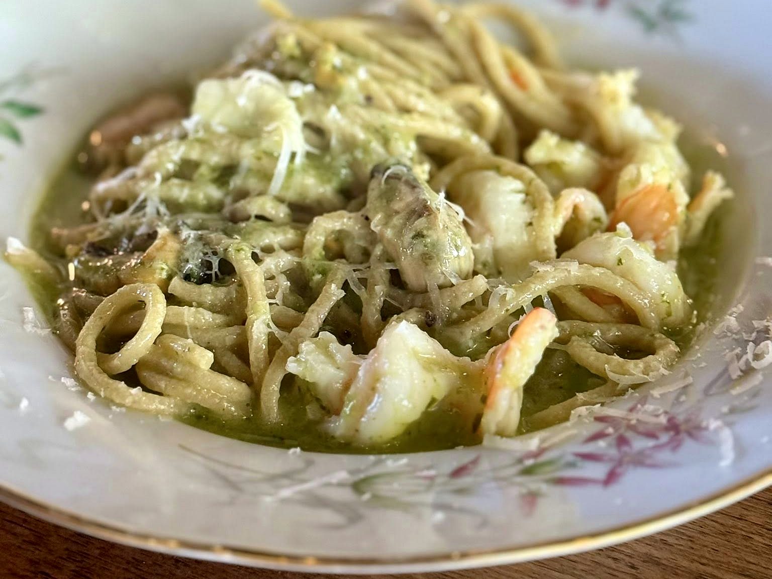 Pesto spaghetti with shrimp at Osteria Bianchi — hand-cut strands slicked green, with mushrooms and shaved parmesan.