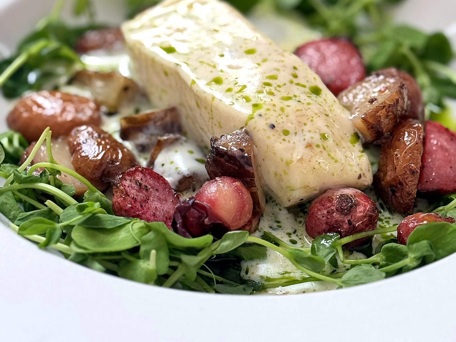 Halibut at Bin 707 Foodbar in an herb-flecked beurre blanc with roasted radishes, potatoes, and pea shoots.