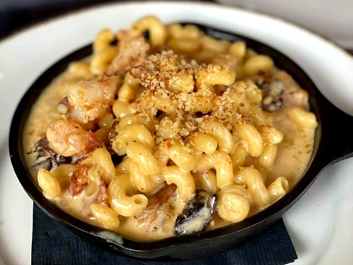 Low-country mac and cheese at The Brass Onion — cavatappi with shrimp and bacon in a cast-iron skillet under toasted crumbs.