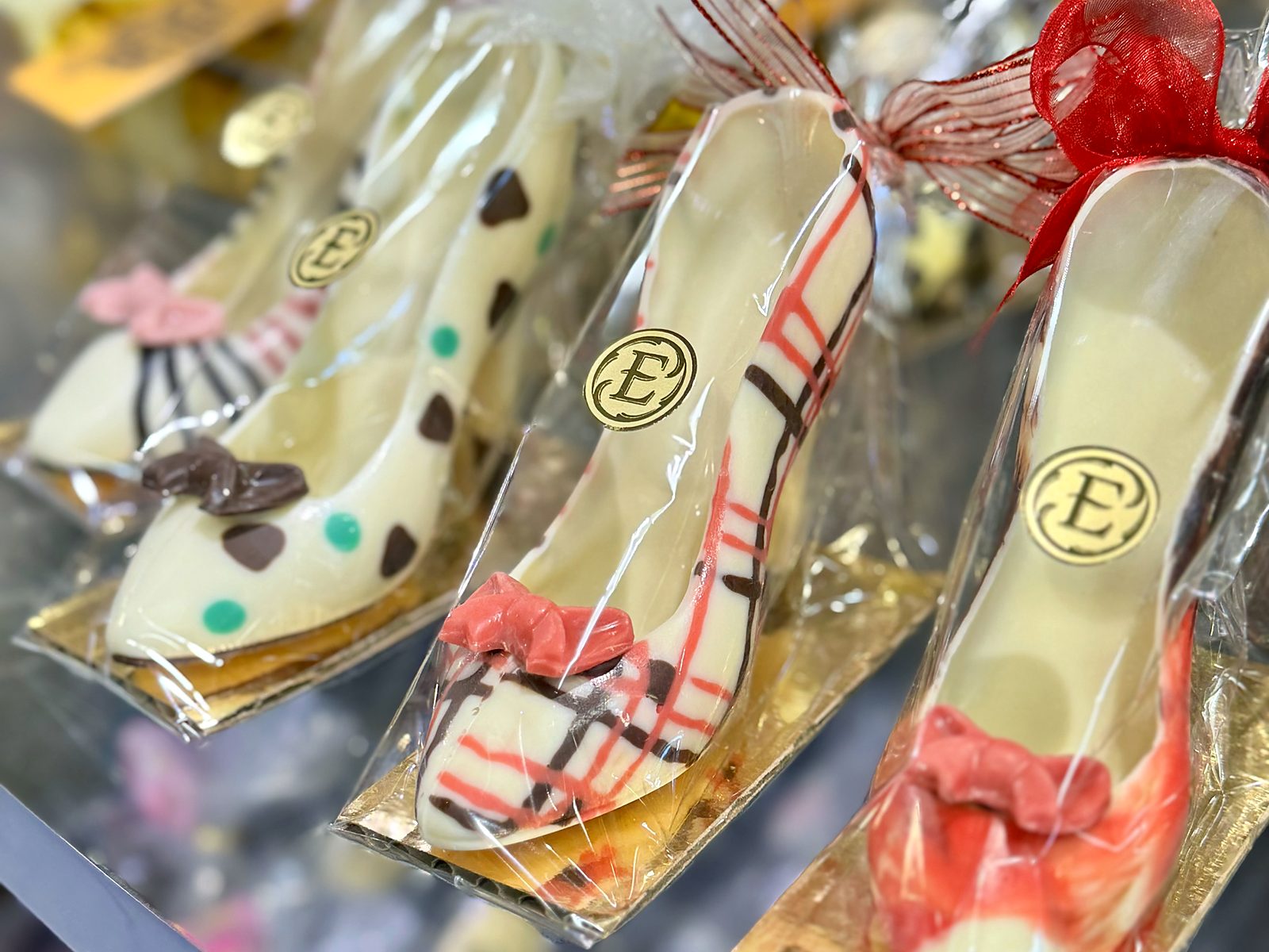 Chocolate high‑heeled shoes at Enstrom &mdash; white and pink chocolate piped with stripes and polka dots, each finished with a candy bow and stamped with the Enstrom E.