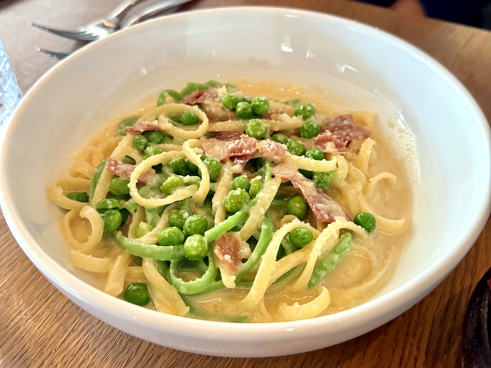 Two-tone pasta at Farina in a silky cream sauce with sweet peas, prosciutto, and grated cheese.