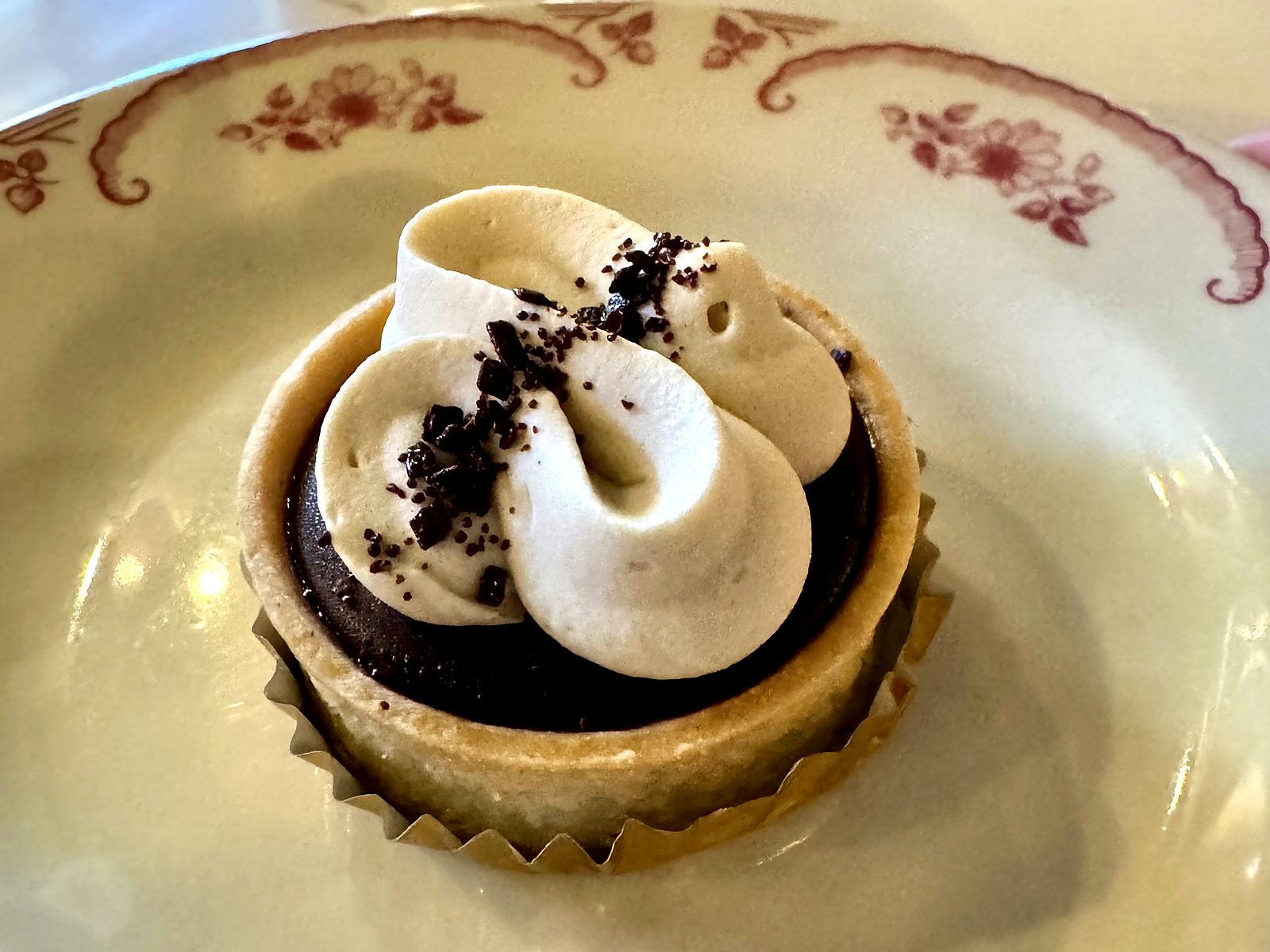 The dark chocolate caramel torte at The French Market — a small tart of glossy dark ganache under swirled cream and chocolate shavings.