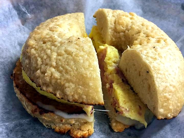 The parmesan bagel breakfast sandwich at Main Street Bagels — folded egg, ham, and melted cheese inside a parmesan-crusted bagel on bakery paper.
