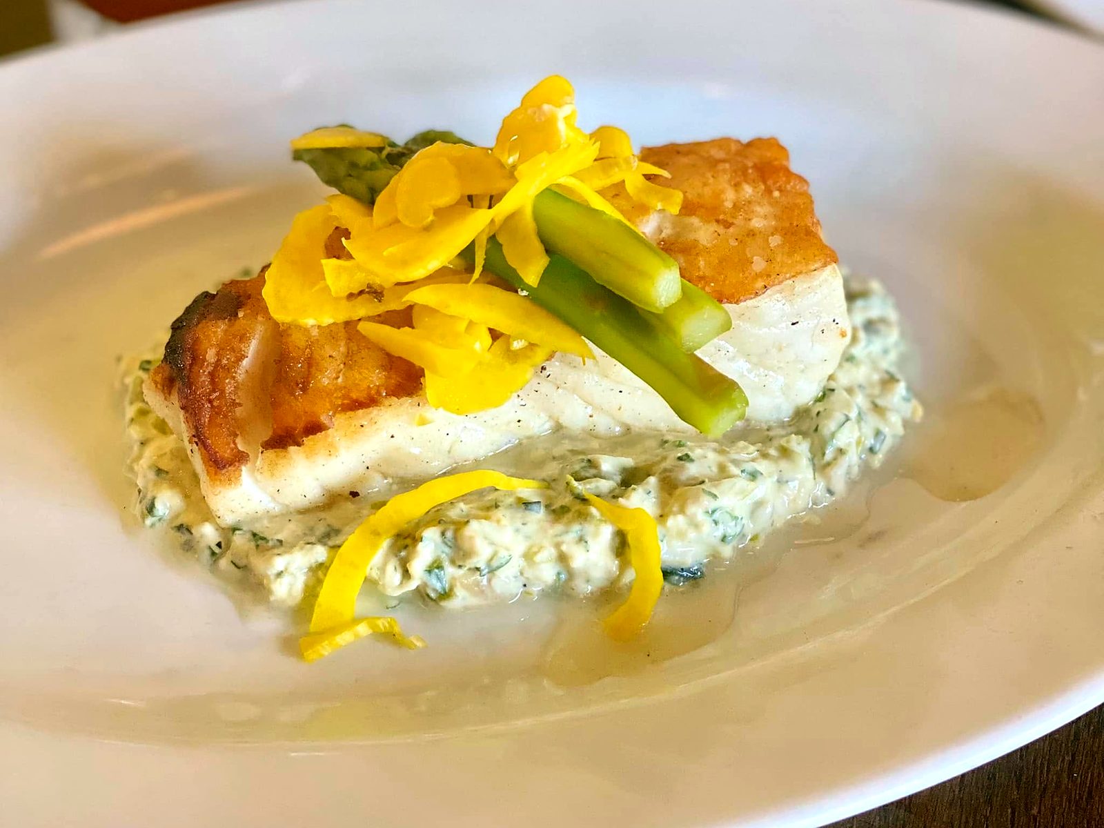 Crispy-skinned fish at Novel — a seared fillet over herbed tartar cream, topped with asparagus and ribbons of pickled yellow squash.