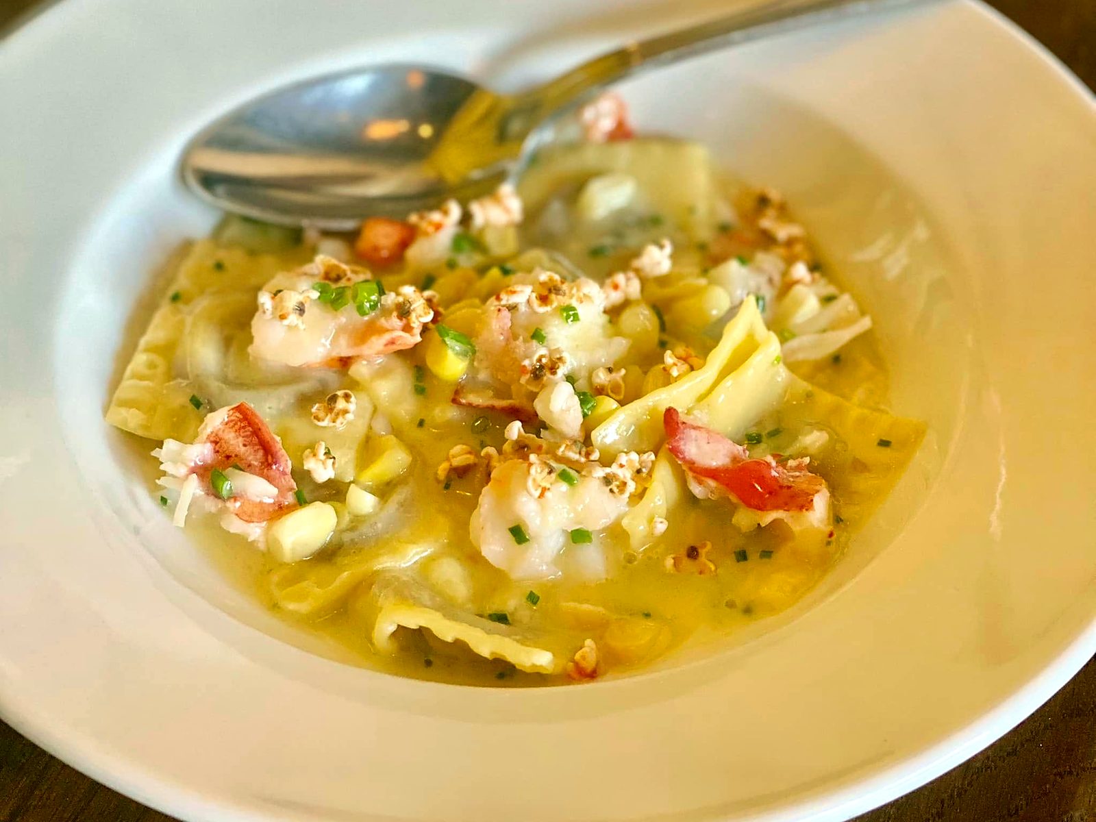 A seasonal pasta at Novel — lobster and shrimp with sweet corn in a golden corn-butter broth, finished with chives and a scatter of popcorn.