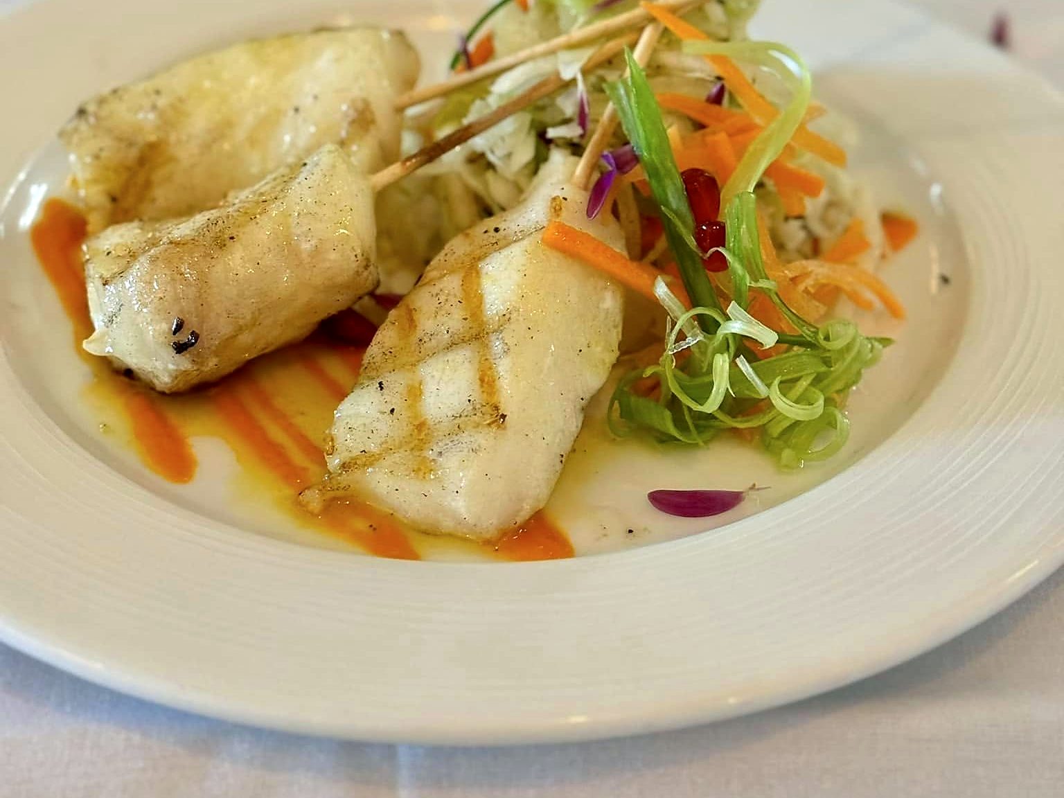 Chilean sea bass souvlaki at Paros — grilled skewered fillets over a swipe of roasted red pepper sauce, with a shaved-vegetable slaw.