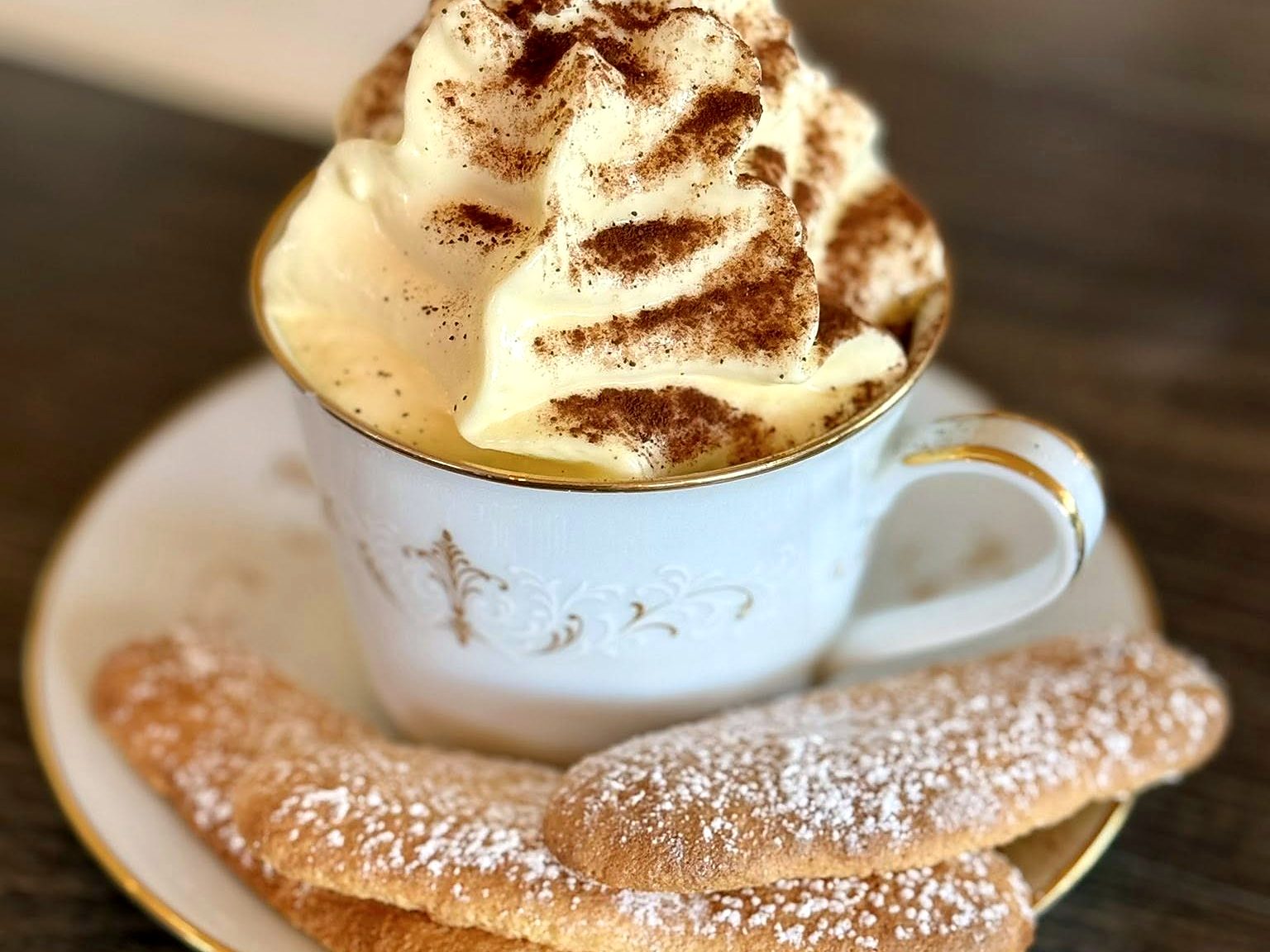 Coffee at Pêche — piled high with cocoa-dusted whipped cream, sugared ladyfingers alongside.