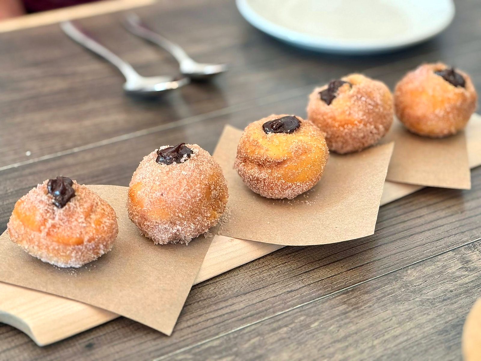 Sugared doughnuts at Pêche — five little rounds filled with dark chocolate, lined up in a row.
