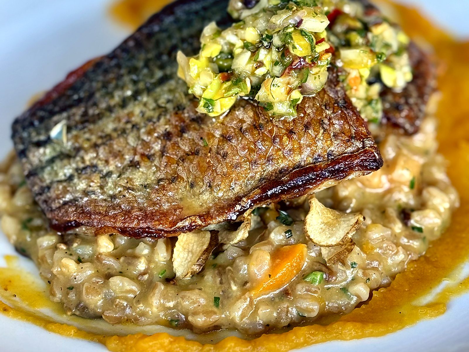 Crispy-skin striped bass at The Pullman over creamy grains and squash purée, topped with pistachio relish.