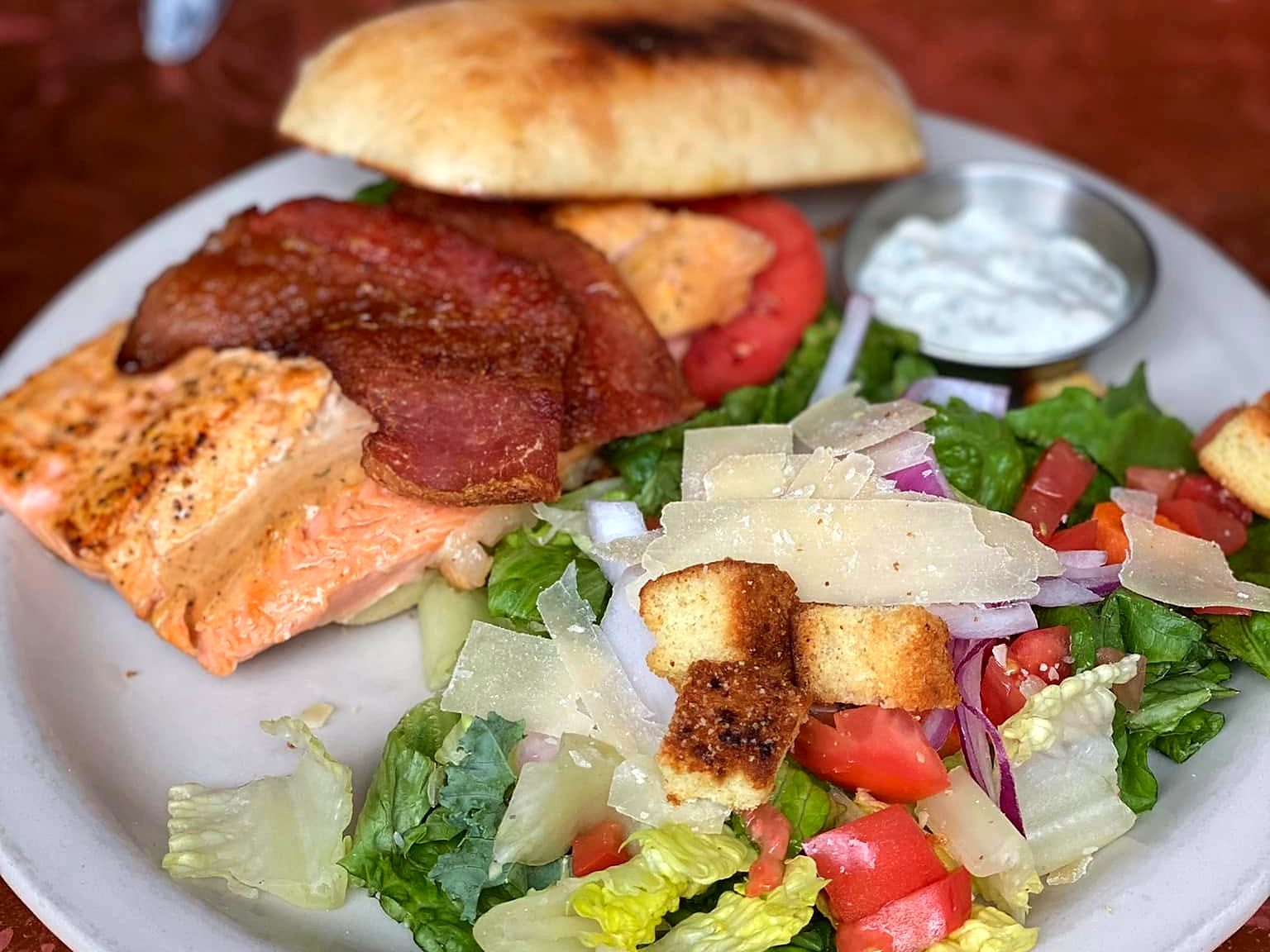 The salmon B.L.T. at CO. Ranch House — a seared fillet under thick bacon on a toasted bun, with a parmesan side salad.