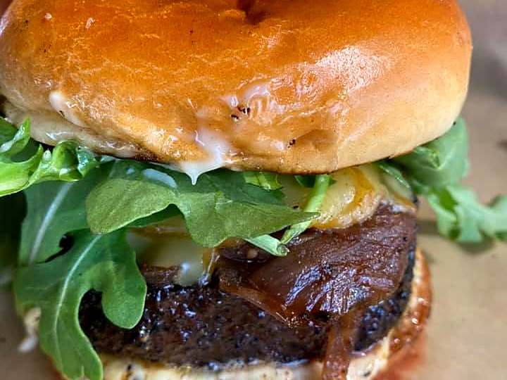 The burger at The Russell — charred patty, melted cheese, caramelized onions, and arugula on a glossy brioche bun.