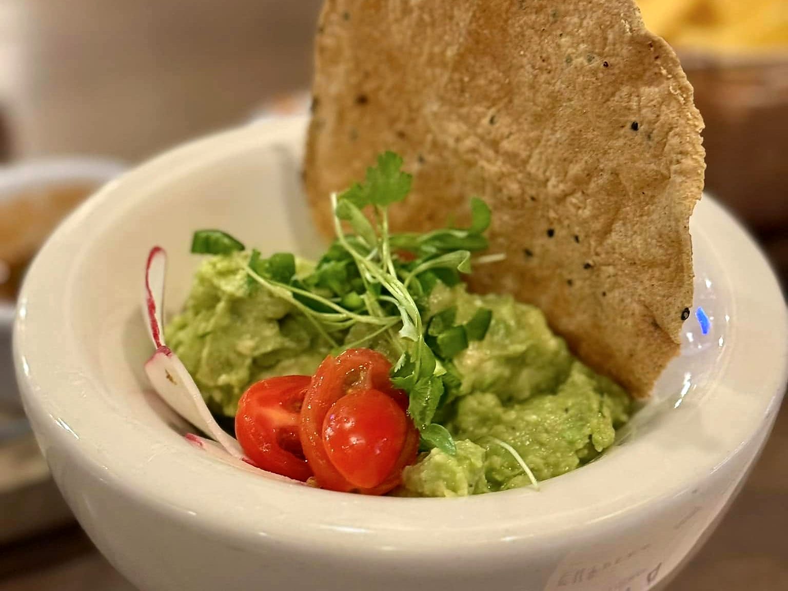 Guacamole at T’ähä with cherry tomatoes, radish, cilantro, and a charred tostada.