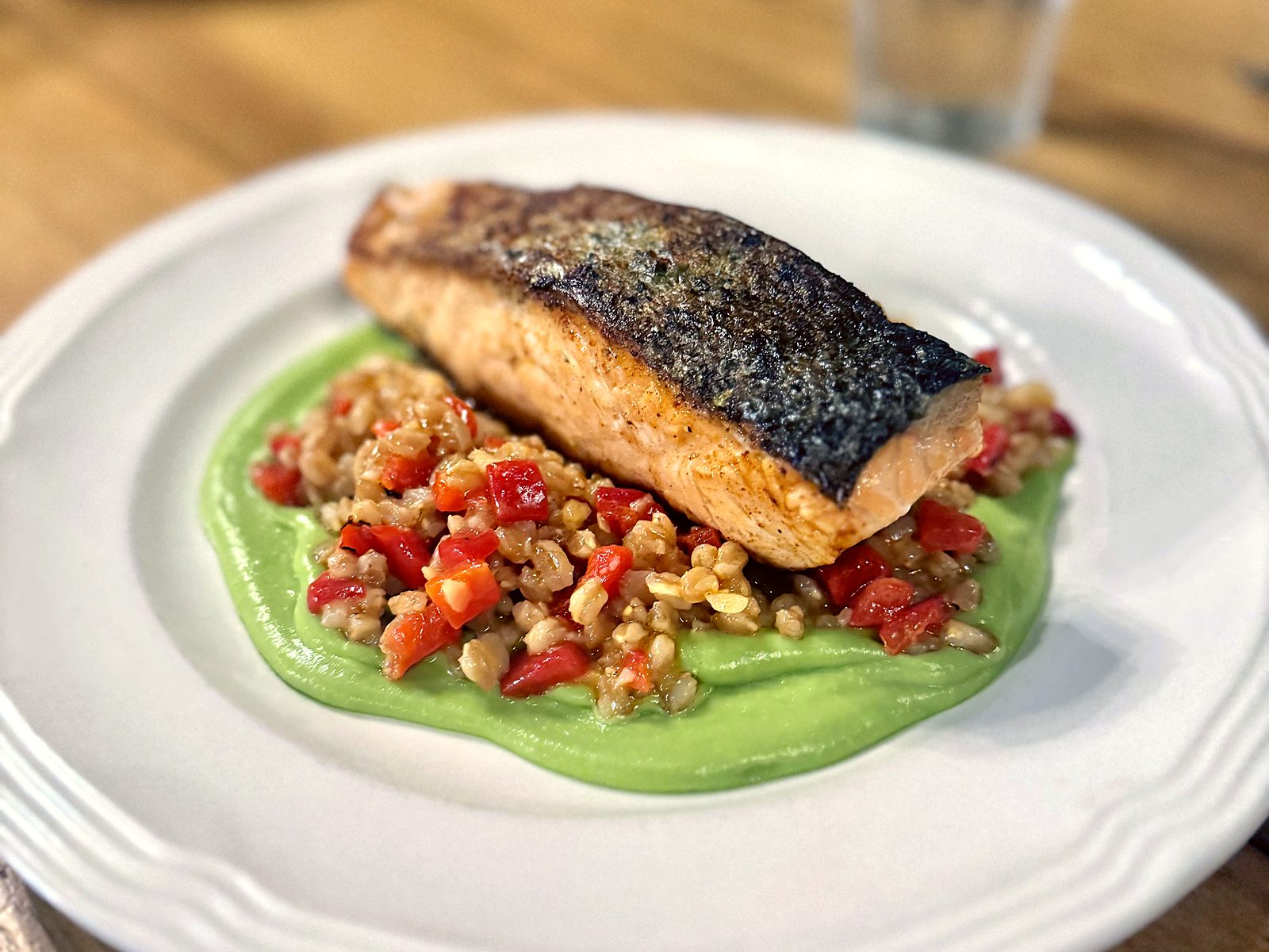 Crispy-skin salmon at Tailleur, plated over farro with red peppers on a bright green purée.