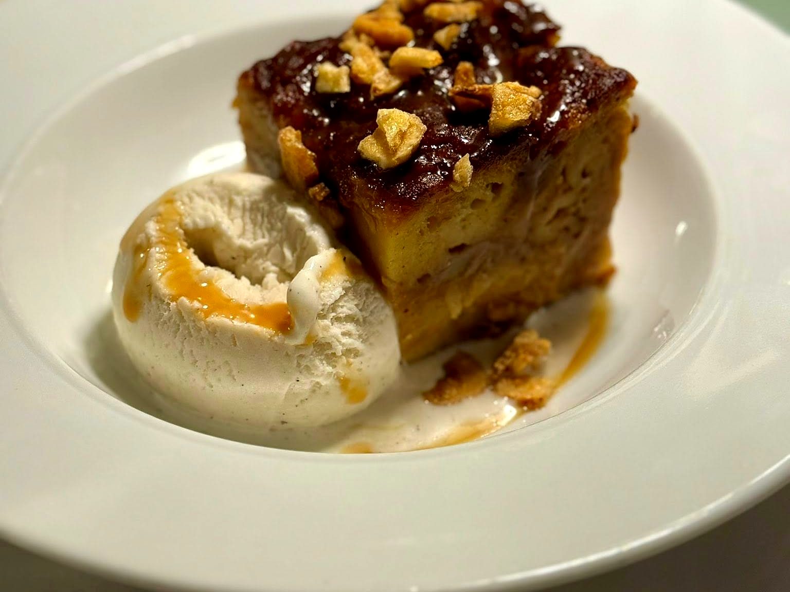 Bread pudding at Verbena — a caramel-glazed square scattered with apple chips, melting into a scoop of vanilla ice cream.