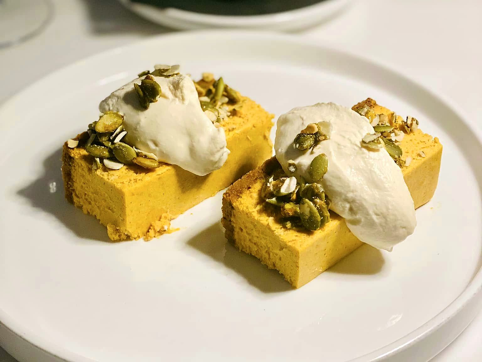 Pistachio cheesecake at Verbena — two golden squares topped with whipped cream, candied pistachios, and toasted almonds.