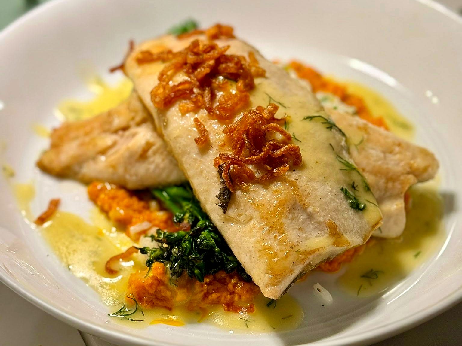 Pan-seared rainbow trout at Verbena — crossed fillets under crispy shallots, over romesco, rice pilaf, and broccolini with lemon-dill vinaigrette.