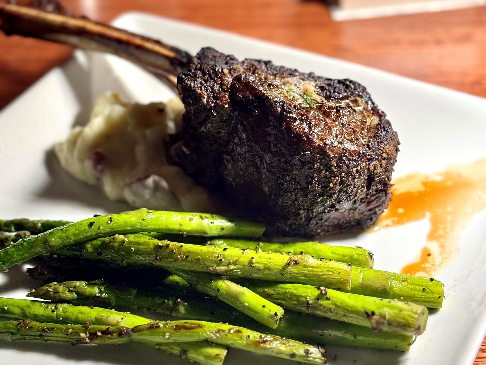 A long-bone lamb chop at Wilder’s Steakhouse — pepper-crusted and butter-basted, over red-skin mashed potatoes with grilled asparagus.